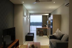 a living room with a couch and a kitchen with a view at Sandpiper Villas Chobe in Kasane