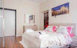 una camera bianca con un grande letto con cuscini rosa di Rodica Comfort Home Milano Navigli a Milano