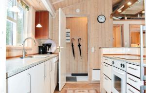a kitchen with white cabinets and a clock on the wall at Holiday Home Krondyrstien Væggerløse Denm in Marielyst
