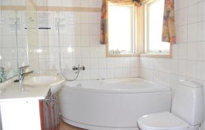 a bathroom with a tub and a toilet and a sink at Holiday Home Krondyrstien Væggerløse Denm in Marielyst