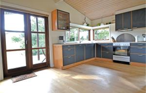 a large kitchen with blue cabinets and windows at 4 Bedroom Stunning Home In Fan in Fanø