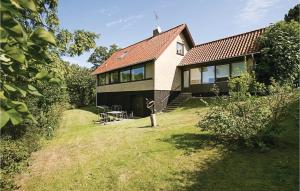 a house with a red roof on a grass field at Cozy Home In Svaneke With Kitchen in Svaneke