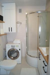 a bathroom with a toilet and a shower and a washing machine at Apartament-Mój AZYL in Mrągowo