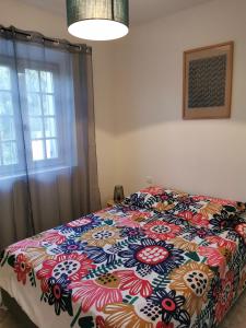 een slaapkamer met een bed met een kleurrijk dekbed bij Aux portes du Luberon in Cheval-Blanc +24 foto's