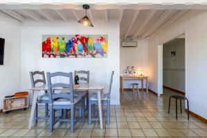 a dining room with a table and chairs and a painting of parrots at La Brie à 15mn de Disneyland et Village Nature in Neufmoutiers-en-Brie