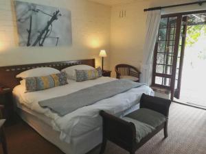 a bedroom with a large bed and a chair at Le Petit Vignoble in Cape Town