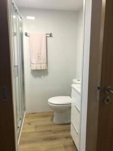 a white bathroom with a toilet and a towel at Casa Moinhos do Rio in Paredes