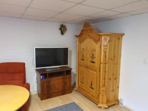 ein Wohnzimmer mit einem TV und einem Holzschrank in der Unterkunft Zimmervermietung Cottbusser Ostsee in Cottbus