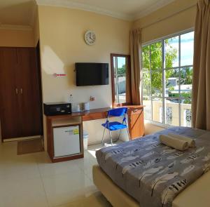 a bedroom with a bed and a desk and a tv at Hulhan'gu Lodge in Himmafushi