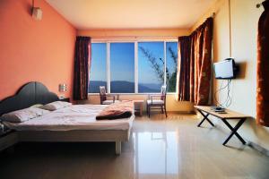 a bedroom with a bed and a large window at Tranquil Treasure in Panchgani