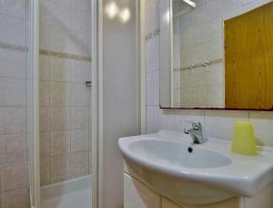 a bathroom with a sink and a mirror and a shower at Apartments Eufemija in Rab