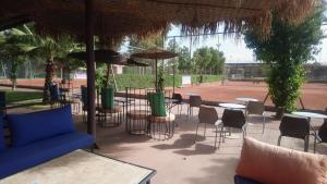 a patio with tables and chairs under an umbrella at L'AUBERGE DE TENNIS MSC in Marrakech