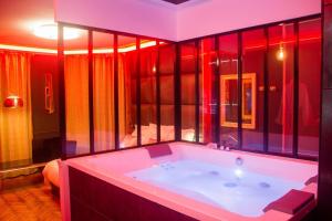 baño con bañera grande con iluminación roja en L'Espace Privé 2 Rouen en Ruan