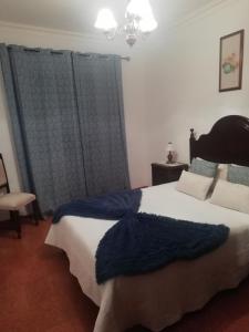 una camera da letto con un grande letto con una coperta blu sopra di Casa da tia Bina a Monsaraz