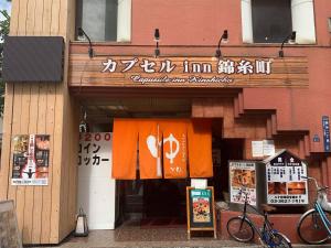 una tienda frente a un edificio con un cartel en Capsule Inn Kinshicho, en Tokio