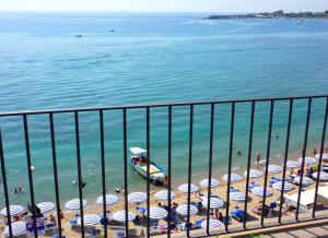 a beach with a bunch of umbrellas and people on the beach at Hotel Palladio in Giardini Naxos