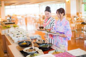 two women are holding plates of food on a buffet at Kyukamura Iwate-Amiharionsen in Shizukuishi
