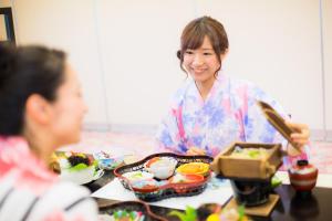 a woman sitting at a table eating food at Kyukamura Iwate-Amiharionsen in Shizukuishi