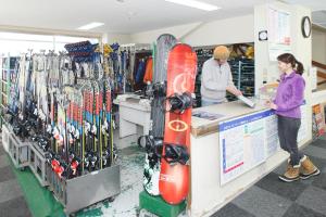 a woman standing at a counter in a store with a snowboard at Kyukamura Iwate-Amiharionsen in Shizukuishi