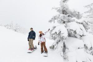 a man and woman standing on snowboards in the snow at Kyukamura Iwate-Amiharionsen in Shizukuishi