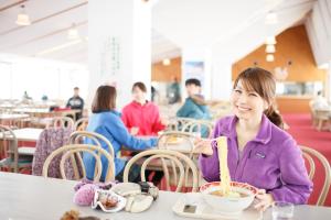 a young girl eating food at a table in a restaurant at Kyukamura Iwate-Amiharionsen in Shizukuishi