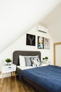 biała sypialnia z łóżkiem z niebieskim kocem w obiekcie V10 Apartment w mieście Pecz