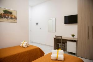 Pokój z 2 łóżkami, biurkiem i telewizorem w obiekcie Stabia Dream Rooms w mieście Castellammare di Stabia