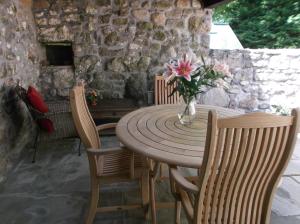 een houten tafel met stoelen en een vaas met bloemen bij new pottery in Penzance