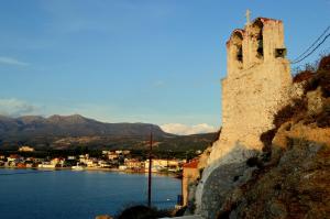 a castle on a hill next to a body of water at Ammos Luxury Suites in Elia Laconias