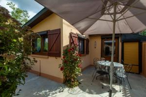 un patio con mesa y sombrilla en GÎTE Le Moulineau en Deville