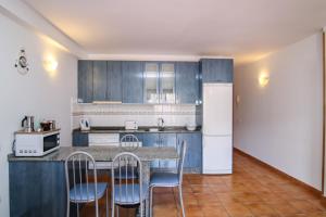 a kitchen with blue cabinets and a table and chairs at VVROMPEOLAS in Puerto de Mogán