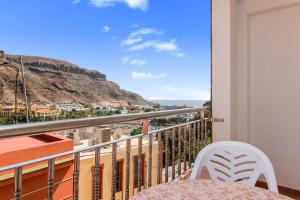 a balcony with a table and chairs and a mountain at VVROMPEOLAS in Puerto de Mogán