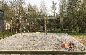a playground with two swings and toys in the sand at Three-Bedroom Holiday Home In Vaggerlose in Marielyst