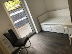 um quarto com uma cama, uma cadeira e uma janela em Apartment Strandläufer em Aurich