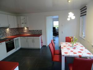 eine Küche und ein Esszimmer mit einem Tisch und roten Stühlen in der Unterkunft Sidowseetraum in Himmelpfort
