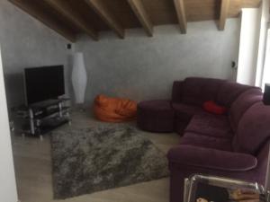 incantevole في Malonno: غرفة معيشة مع أريكة أرجوانية وتلفزيون