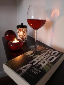a book next to a glass of wine and a candle at Vadóka ház in Őriszentpéter