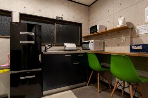 a kitchen with a counter and two green chairs at HOSTEL MICHIKUSA-YA in Fujikawaguchiko