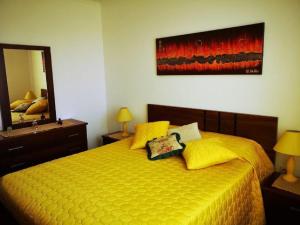 a bedroom with a yellow bed and a mirror at Villa da Silva in Madalena