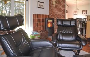 - deux fauteuils en cuir dans le salon avec cheminée dans l'établissement Holiday Home Fyrrekrogen Nørre Nebel Vi, à Lønne Hede