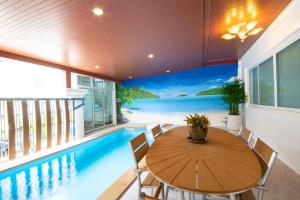 a dining room with a swimming pool and a table and chairs at Rudi House in Patong Beach