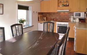 une cuisine avec une table et des chaises noires et une cuisine avec une cuisinière dans l'établissement Holiday Home Fyrrekrogen Nørre Nebel Vi, à Lønne Hede