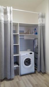 a laundry room with a washing machine and shelves at Joli T2 de 40m² à louer à Le Muy (83490) in Le Muy