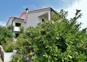a house with a tree in front of it at Apartments Eufemija in Rab