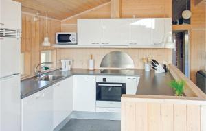 una cocina con armarios blancos y fregadero en Buller, en Fanø