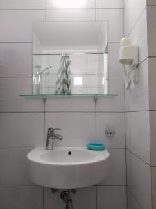 ein Waschbecken im Bad mit einem Glasregal darüber in der Unterkunft Апартаменти Декорум in Schidnyzja