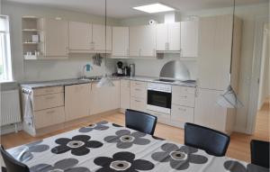 グラセンにあるAmazing Apartment In Grsten With 1 Bedrooms And Wifiの白いキャビネット、テーブルと椅子付きのキッチンが備わります。