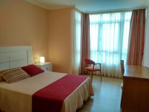 a bedroom with a bed and a chair and a window at CASA CHALET ATALAYA a pie de playa en Laxe in Laxe