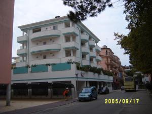 um edifício alto e branco com carros estacionados em frente em Hotel Gran Venere Beach 3 Superior em Bibione