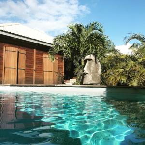 a swimming pool in front of a house with palm trees at Villa Moai 974 in Saint-Leu